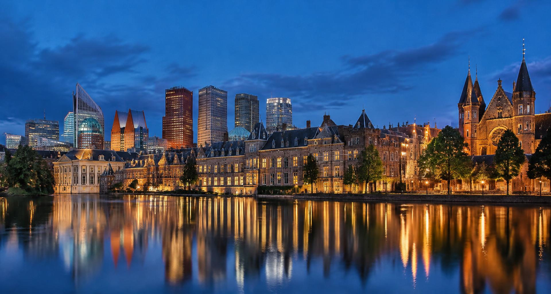 De karakteristieke Binnenhof en de Hofvijver in Den Haag bij avond, met de skyline op de achtergrond